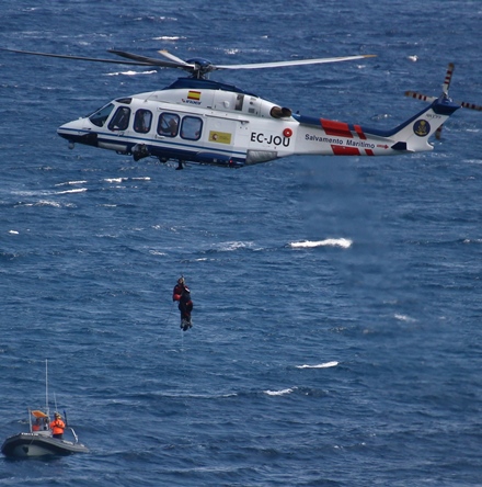 Momento en el que la grúa del helicóptero sube al rescatador y el maniquí utilizado en el ejercicio. En la parte inferior, la lancha de Protección civil de Blanes / Foto: Anna Sais